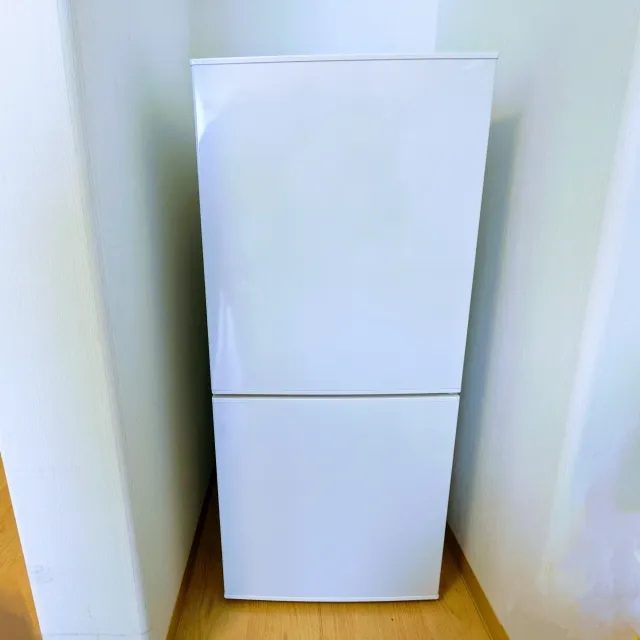 クリーム色の壁に挟まれた狭いスペースに配置された白い2ドア冷蔵庫