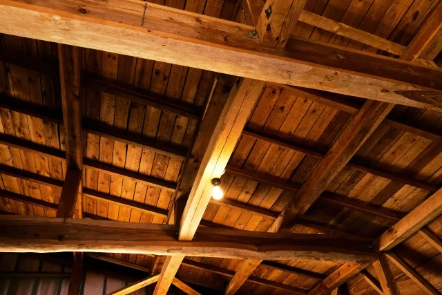 天井から吊り下げられた木製の梁。素朴な造りで、中央には一つの電球が灯されている