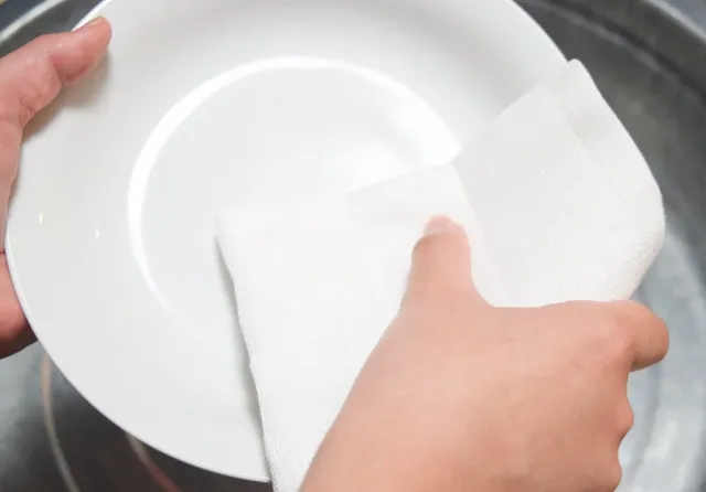 白い皿を白い布巾で拭いている様子